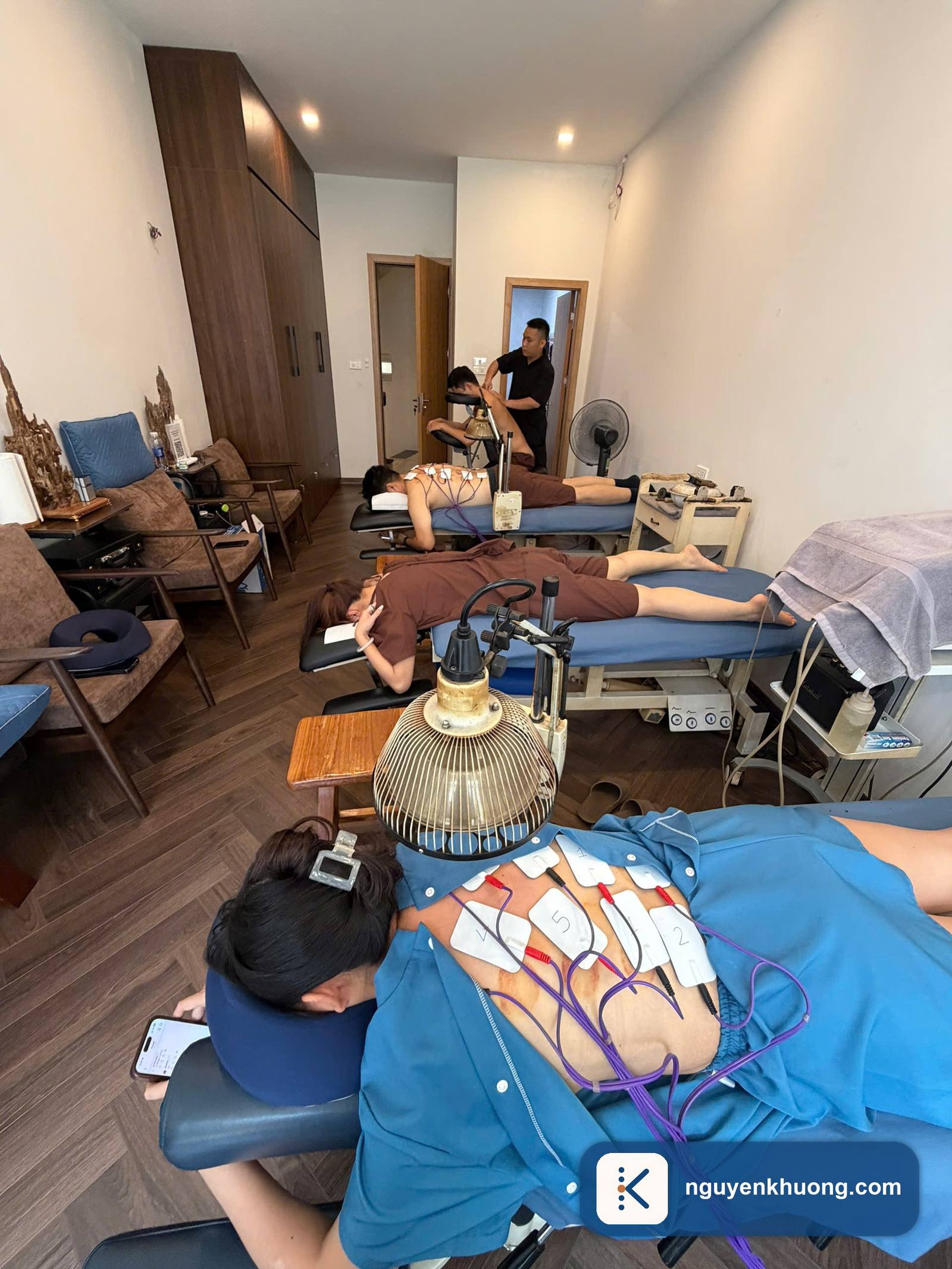 Điện cực máy điện xung đánh số gắn trên lưng khách trong buổi trị liệu phục hồi vận động