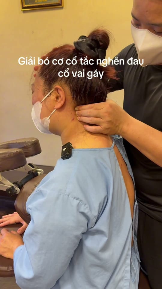 Chuyên gia giải cơ vùng cổ vai gáy cho khách đang ngồi ghế trị liệu